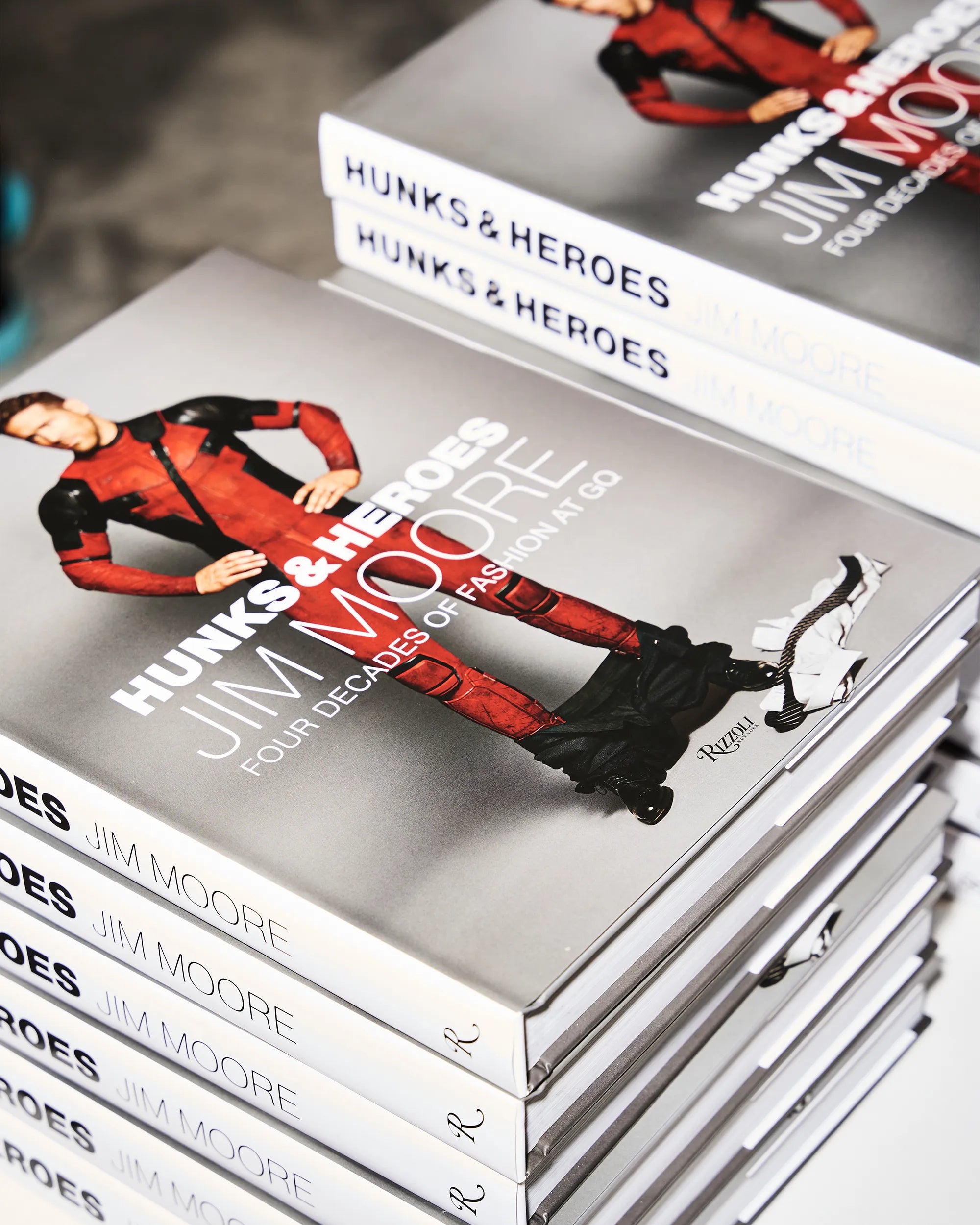 Stack of books titled 'Hunks & Heroes' by Jim Moore on a gray surface.