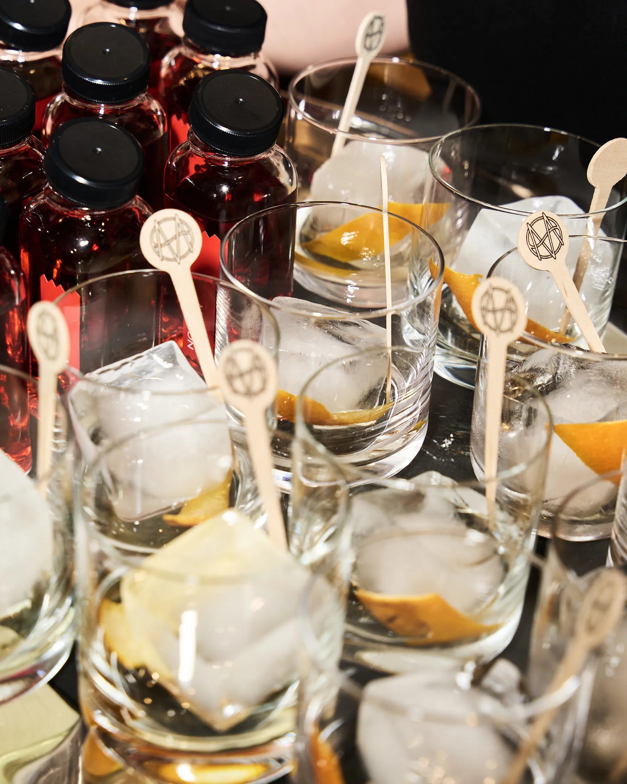 Cocktails with ice and orange peel slices in glasses on a table.