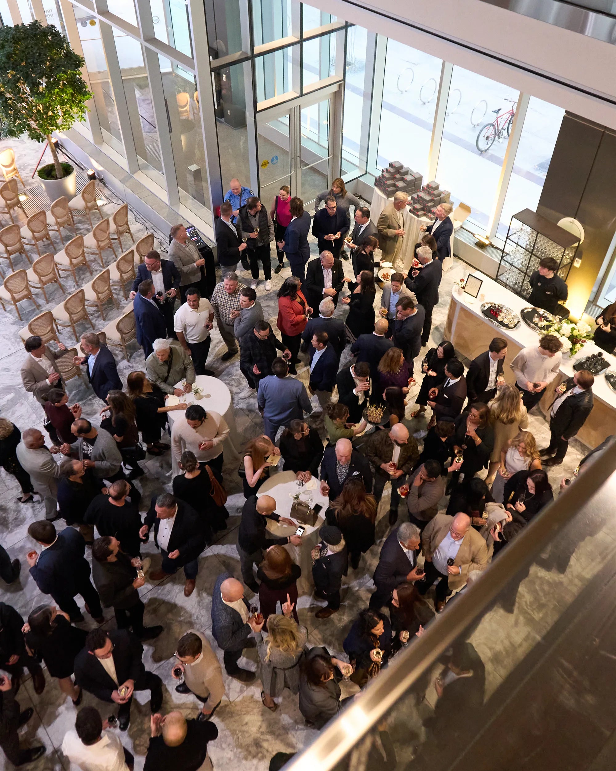 Group of people gathered in a modern indoor setting with large windows.