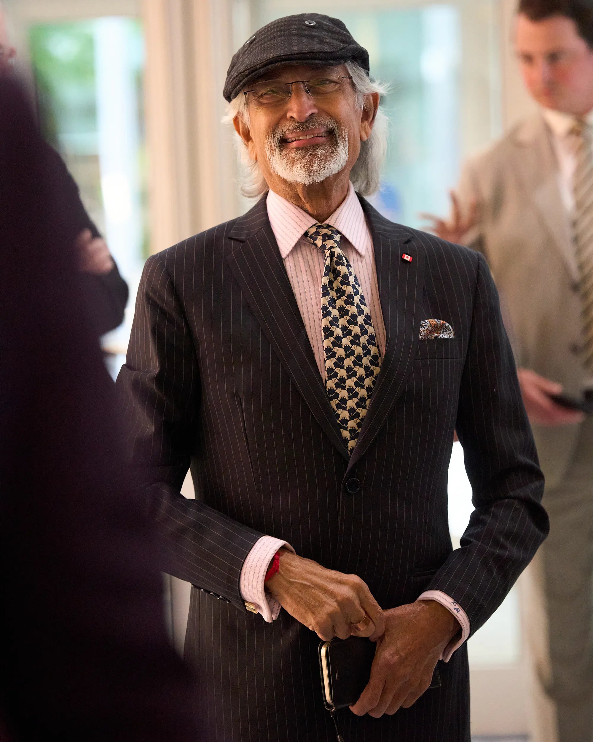Man in a suit with a patterned tie and cap, standing indoors.